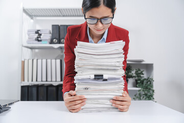 cheerful individual wearing glasses and a red blazer, hard working with large stack of papers,...