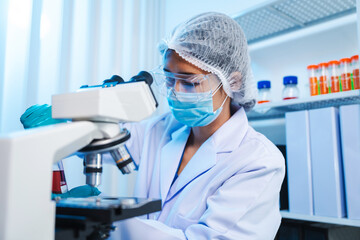 Asian people scientist in lab coat and protective gloves working with test tubes with green and red...