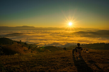 Fototapeta premium Asian Man is happy and relaxed with the scenery of the sea mist a beautiful natural in the morning at Car Camping site on the top of a mountain in winter season at Chiang Mai, Thailand.