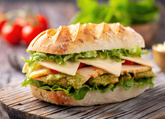 Fresh and healthy pesto turkey sandwich with white cheddar cheese on wooden cutting board.
