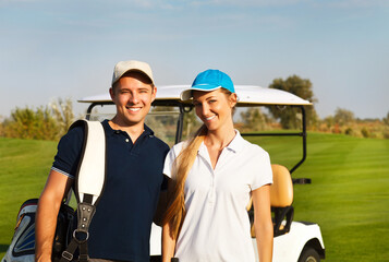 Naklejka premium Young sportive couple playing golf on a golf course
