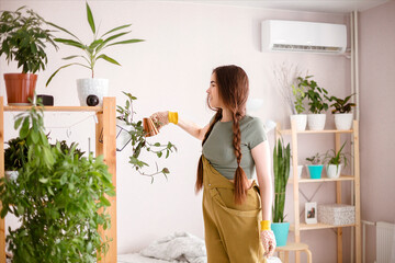 Young woman taking care of plants at home - obrazy, fototapety, plakaty