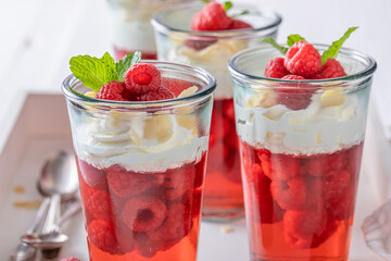 Homemade red jelly served with raspberries in glass .