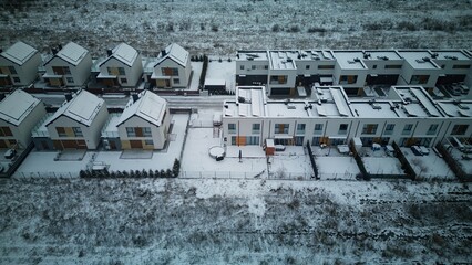 Aerial view of rows of identical houses covered in snow, with solar panels also covered by white...