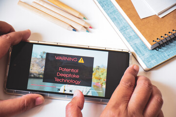 Mobile phone displaying warning message of an artificial video using deepfake technology.