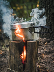 Food is cooked in a metal pot on Swedish Fire Log. Burning a Swedish candle, swedish torch in summer