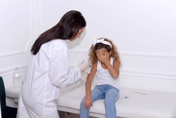 Vaccine fear in children, Little girl in face mask in doctor's office is vaccinated. Crying,...