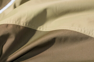 protective work clothes in beige and brown colors. Factory stitches on thick fabric. Close-up texture