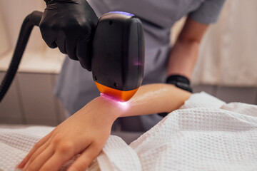 Fototapeta premium Young woman receiving photo epilation while visiting beauty center on salon