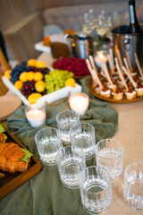 Swiss table at the party. Close up of croissants with greens and glasses with drinks