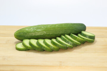 fresh cucumber and sliced cucumber on wooden board

