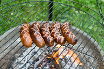 Sausages being barbequed in a garden - 704376501