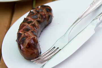 Barbequed Sausage served on a plate in a garden - 704376557