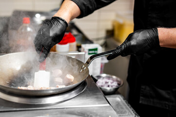 Professional chef cooking chicken food in wok pan on kitchen