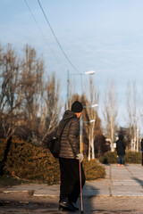 An elderly man, a mustachioed pensioner, walks down the street in the city with a stick in his hand. Photography, old age concept.