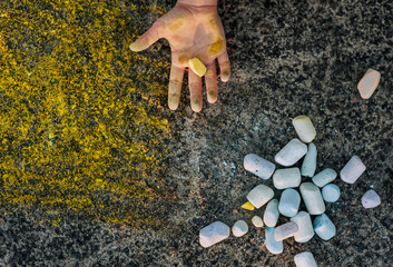 Ukrainian girl, child shows dirty, smeared hands, palms with yellow chalk after drawing a picture on the asphalt. Photography, top view, childhood concept.