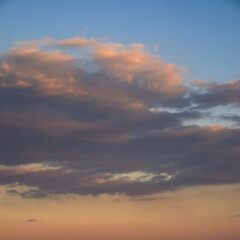 A serene sky with gentle clouds, illuminated by the fading sunlight.