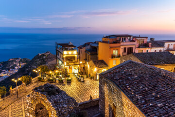 amazing evening view from mountain town to beautiful italian town with roofs and biuldings and scenic water of a sea gulf with amazing cloudy sky on background