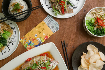 Foods to eat on Lunar New Year’s Eve on the table with golden envelope stuffed with money as a token of good fortune in the New Year.