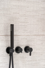 Closeup on modern black matte shower system with head sprinkler on wall