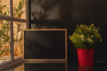 Panorama de fond d'un mur noir et un tableau en ardoise vide pour création d'arrière plan. Panoramique avec jeu d'ombre et de lumière à travers une fenêtre.	