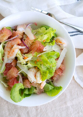 plate with salad with pomelo and shrimp on the table