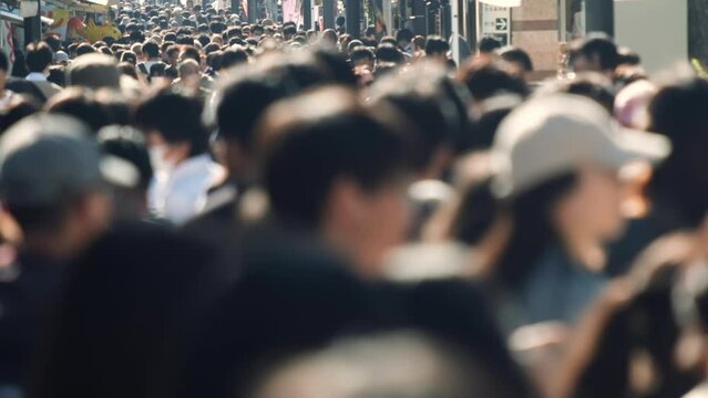 Unfocused blurry crowd of people walking in the street. Slow motion.