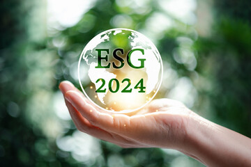 Hand holding globe with 2024 green ESG on nature background. 2024 Green business, environmental...