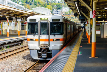 Local train arrive to railway station platform in Japan. Train transportation concept. - obrazy, fototapety, plakaty