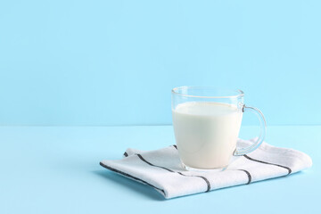 Glass cup with fresh milk on blue background