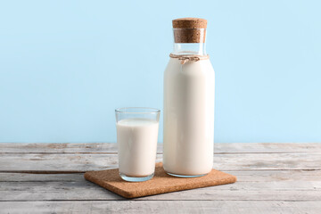 Bottle and glass with fresh milk on grey wooden table