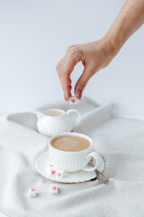 on a white background, a white cup with coffee, around refined sugar with hearts