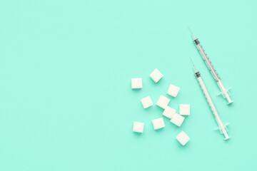 Sugar cubes with syringes for insulin injection on green background