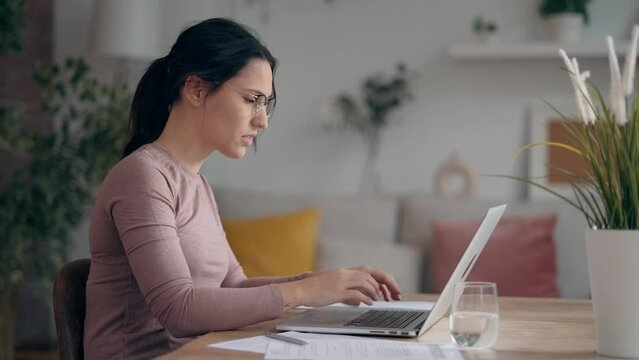 Video of worried angry businesswoman working with laptop while having problems in living room at home