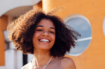 Happy African-American teenage girl is genuinely smiling outdoors. Attractive dark-skinned teenage...