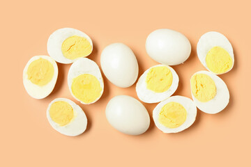 Tasty boiled eggs with halves on orange background