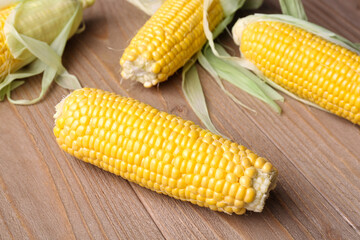 Fresh corn cobs on wooden background