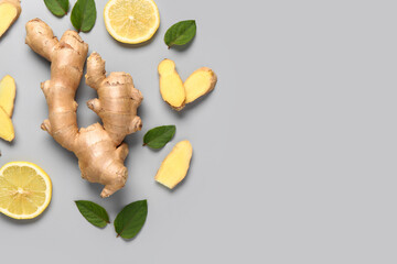 Fresh ginger root with slices of lemon and leaves on grey background