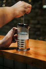 Fototapeta na wymiar barista hand preparing a milk cream inside a cozy coffeeshop