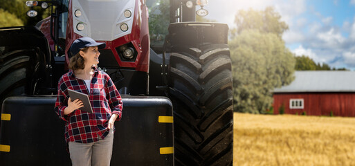 Woman farmer with a digital tablet on the background of an agricultural tractor