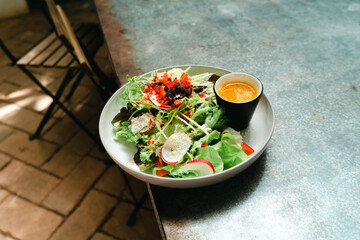 Beet summer salad with arugula, radicchio, on plate, dressing and spices on table, top view. Salad bowl with green salad. Fresh Green vegan salad from green leaves mix and vegetables.