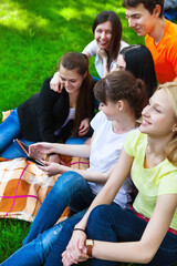 Students using tablet computer while doing homework in the park