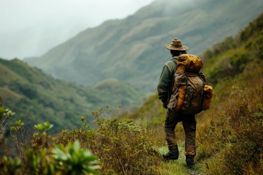 A solitary figure braves the rugged terrain, surrounded by lush green grass and towering mountains, their clothing blending seamlessly with the natural world as they immerse themselves in the raw bea