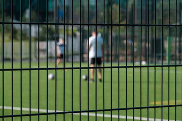 Two unfocused silhouettes of adult males playing soccer in the field.