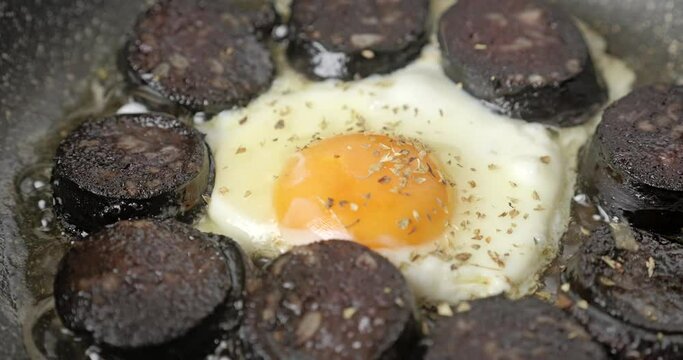 Cooking of homemade blood sausages and egg on a frying pan