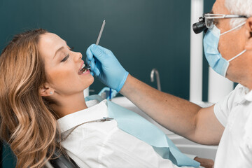 The dentist examines the patient's teeth with great attention and professionalism, studying every...