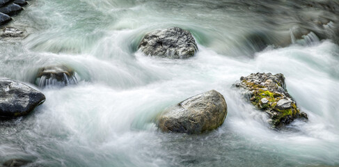 Fresh flowing water around boulders ina creek in the Yellowstone National Park, long exposure © Martina