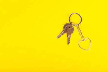 Heart-shaped keychain with key ring ion a colored background. Concepts for real estate and moving home or renting property. Buying a property. Mock-up keychain.Copy space.