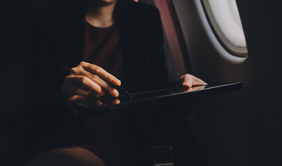 Blonde female tourist checking incoming notification on smartphone sitting on seat of airplane with...