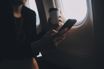 Blonde female tourist checking incoming notification on smartphone sitting on seat of airplane with...